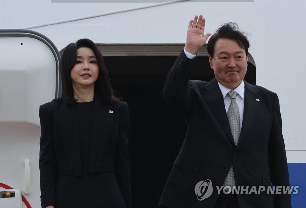 9月18日，在位于京畿道城南市的首尔机场，韩国总统尹锡悦（右）和夫人金建希在总统专机“空军一号”舷梯上向送行人群致意。 韩联社