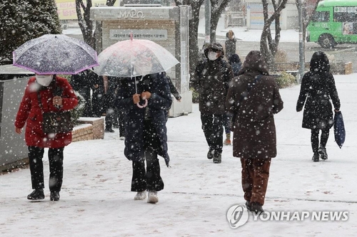 资料图片：12月15日，在首尔麻浦区，市民们撑着雨伞在雪中出行。 韩联社