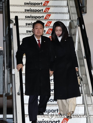 当地时间1月17日下午，韩国总统尹锡悦（左）和夫人金建希乘坐总统专机“空军一号”飞抵苏黎世国际机场，图为尹锡悦伉俪走下悬梯。 韩联社。