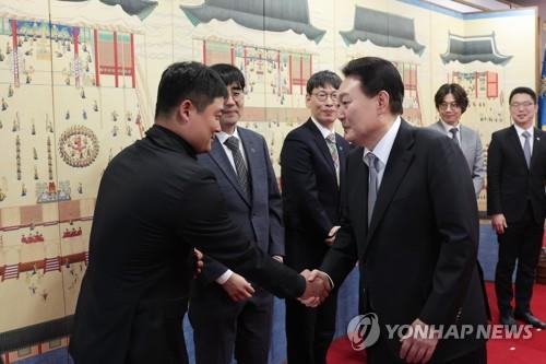 1月24日，在首尔龙山总统府，韩国总统尹锡悦（右）与应邀出席午餐会的科学家们握手致意。 韩联社/总统办公室供图（图片严禁转载复制）
