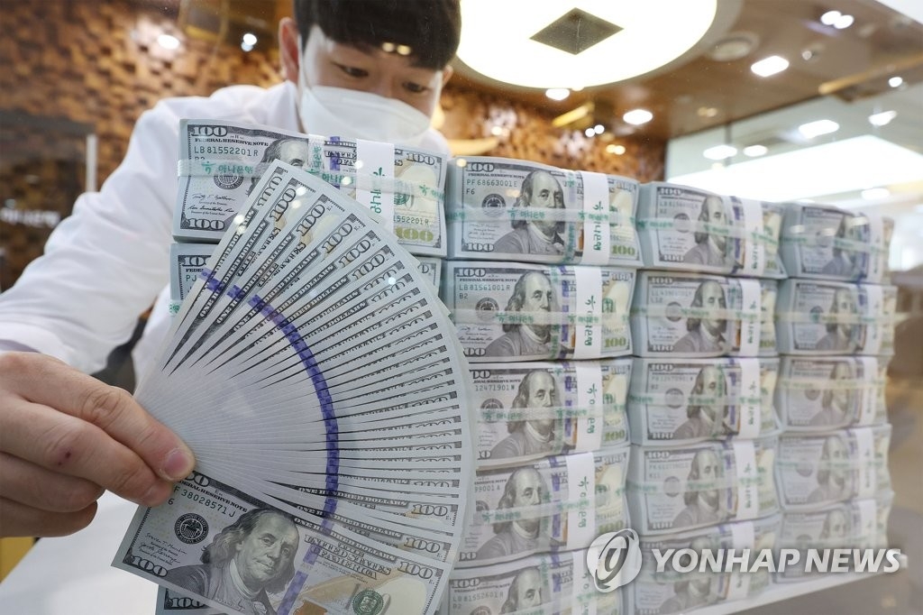 资料图片：银行工作人员清点美钞。 韩联社