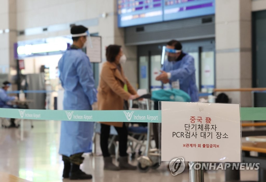 资料图片：2月12日，在仁川国际机场，来自中国的入境人员接受工作人员有关核酸检测的指引。 韩联社