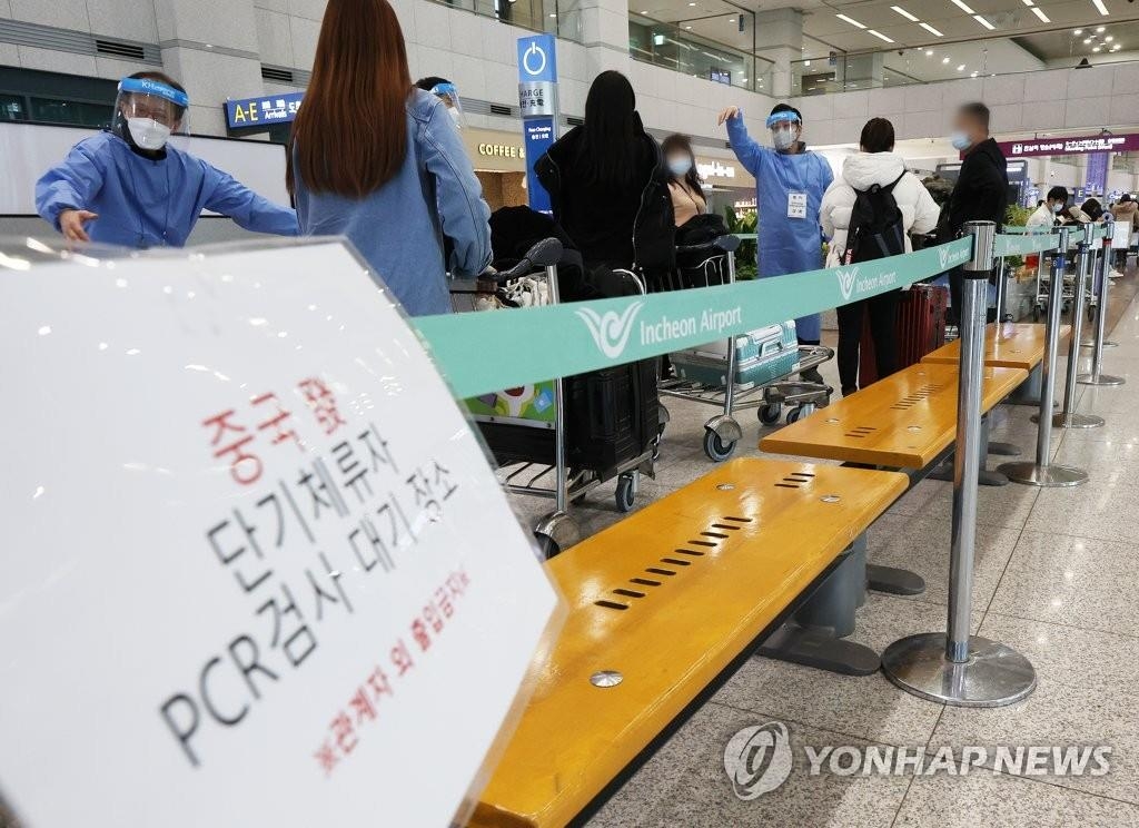 资料图片：2月9日，在仁川国际机场第一航站楼入境大厅，来自中国的旅客接受防疫工作人员的指引。 韩联社