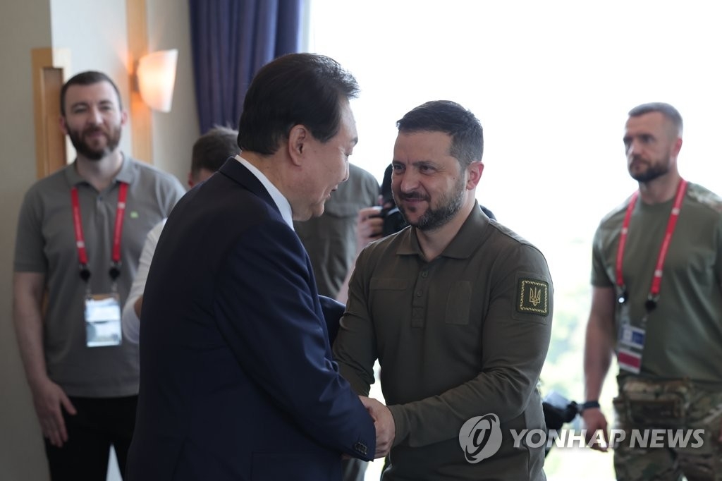 资料图片：5月21日，在日本广岛格兰王子大酒店，尹锡悦（左）与泽连斯基在韩乌首脑会谈上握手致意。 韩联社/联合采访团