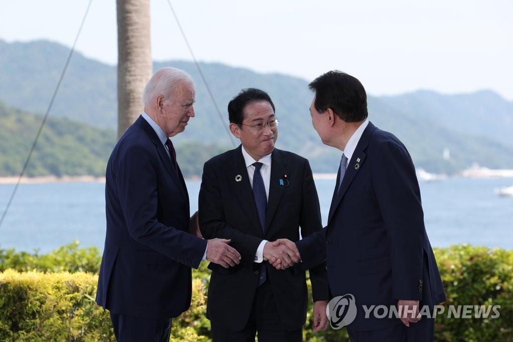 资料图片：5月21日，在日本广岛，韩国总统尹锡悦（右）和美国总统拜登（左）、日本首相岸田文雄在会谈前握手致意。 韩联社/联合摄影团 