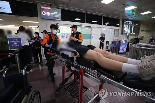 5月26日，在大邱国际机场，韩亚航空OZ8124客机因舱门打开事故紧急降落。图为该机部分乘客被送医。 韩联社