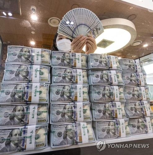 资料图片：韩亚银行总行员工清点美钞。 韩联社
