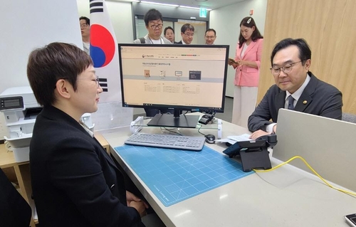 李度勋（右）体验在外同胞服务支援中心接待工作。 韩联社