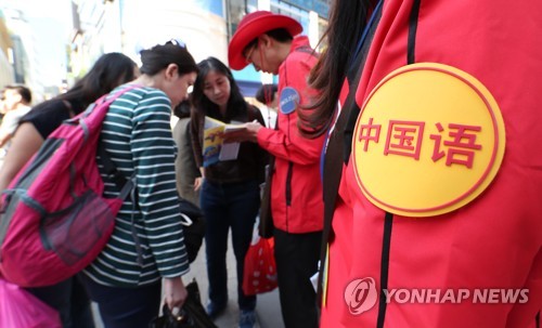 资料图片：2018年5月4日，在首尔明洞大街，韩国导游向中国游客提供帮助。 韩联社