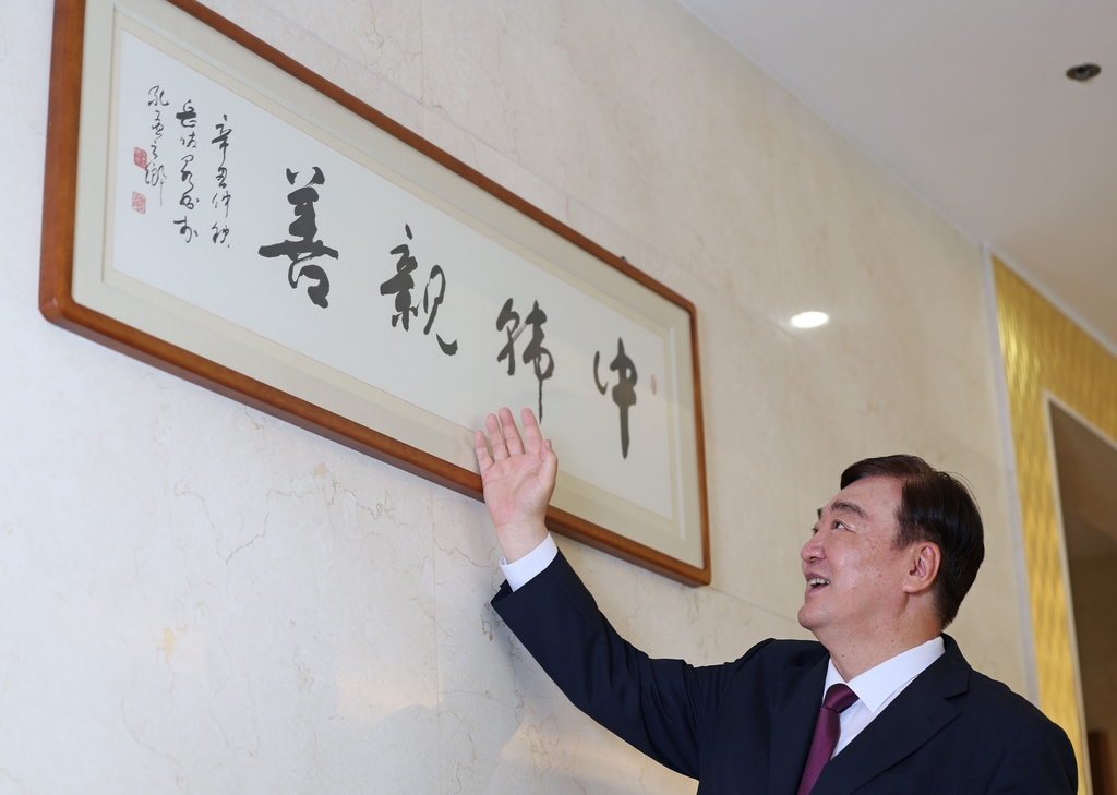 8月18日，在位于首尔中区的中国驻韩大使馆，邢海明向记者介绍使馆内的“中韩亲善”书法作品。 韩联社
