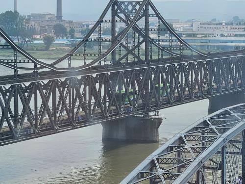 资料图片：8月16日，在鸭绿江大桥上，两辆大巴从新义州驶向丹东。 韩联社