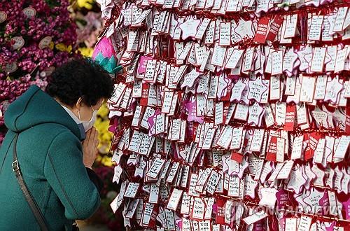 资料图片：11月15日，在首尔钟路区的曹溪寺，一名市民为考生祈福。 韩联社