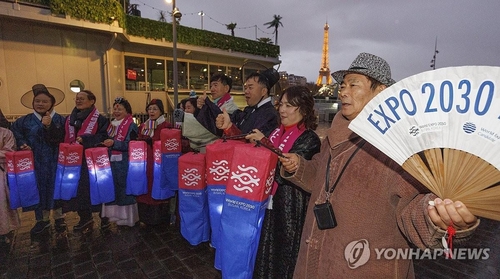 资料图片：当地时间11月27日，在法国巴黎塞纳河畔，宣传釜山世博的公民团体成员们手持青纱灯笼高喊加油，祈愿申博成功。 韩联社