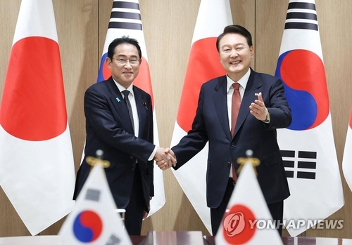 资料图片：5月7日，在首尔龙山总统府，韩国总统尹锡悦（右）与日本首相岸田文雄握手合影。 韩联社