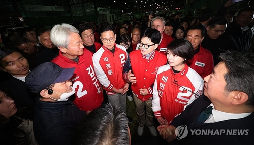 3月28日，在首尔可乐洞农水产品批发市场，执政党国民力量紧急对策委员会委员长韩东勋（右三）与市民握手拜票。 韩联社/联合采访团