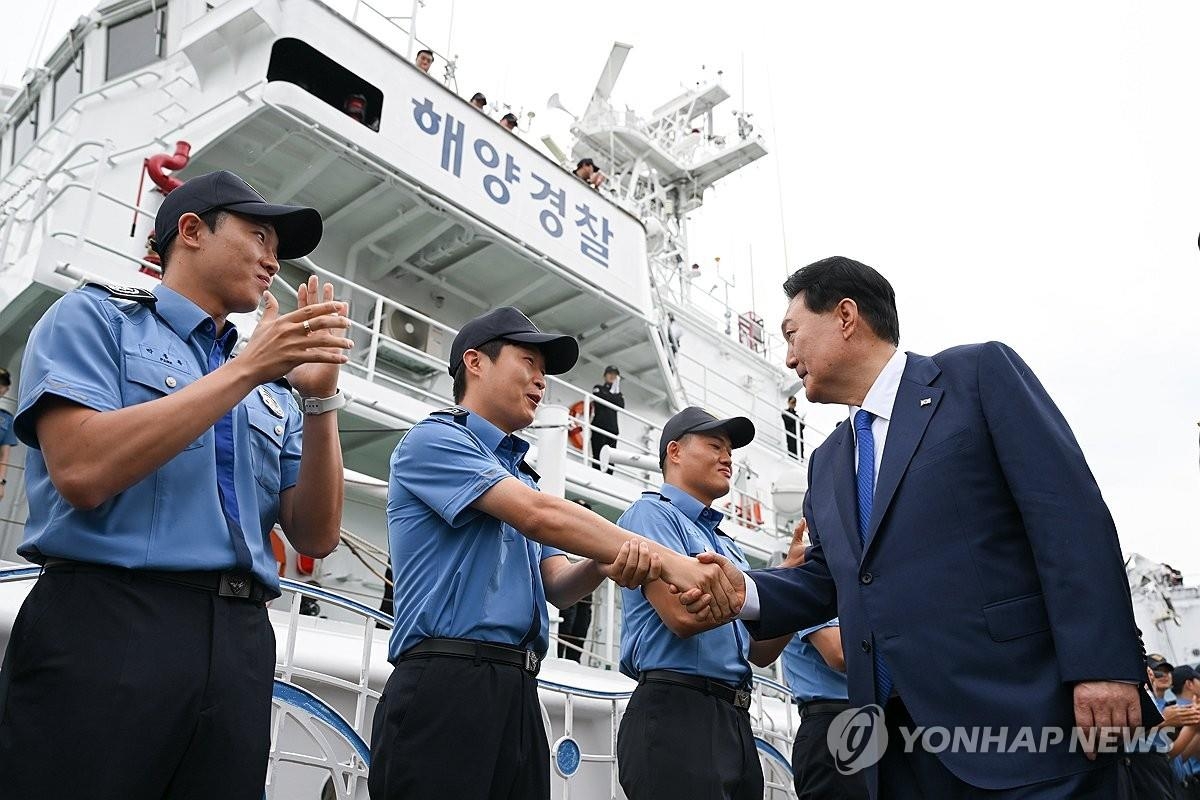 资料图片：2023年8月28日，在韩国海警3005巡逻舰前，尹锡悦（右）勉励海洋警察。 韩联社/总统室供图（图片严禁转载复制）