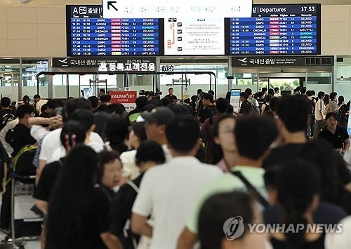 7月19日，在济州机场易斯达航空的开票柜台，旅客排长队等候办理开票手续。 韩联社