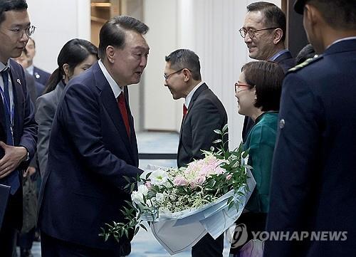 当地时间10月7日，在新加坡樟宜机场，韩国总统尹锡悦（左）从前来迎接的人士手中接过鲜花。 韩联社