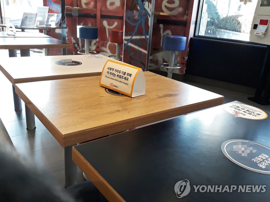 资料图片：咖啡馆桌上的“保持社交距离”提示牌 韩联社