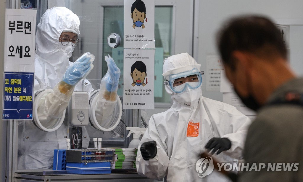 资料图片：在一处新冠筛查诊所，医务人员进行新冠病毒检测。 韩联社