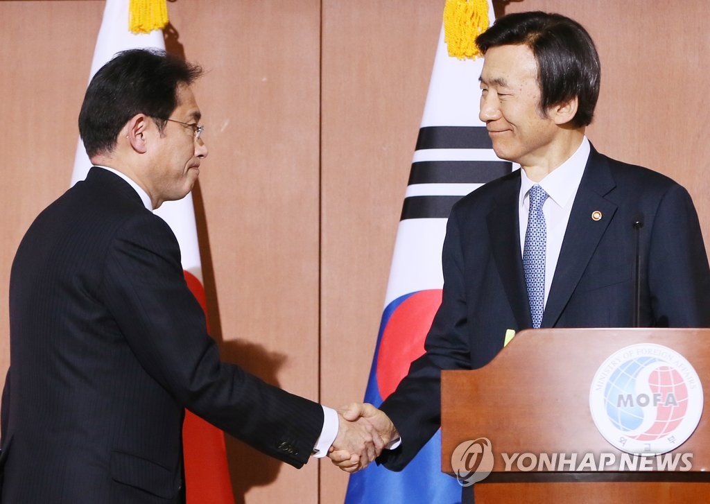 资料图片：2015年12月28日，在首尔外交部办公大楼，韩国外交部长官尹炳世（右）和日本外相岸田文雄在会谈结束后亲切握手。当天，双方进行“慰安妇问题谈判”，并达成一致意见。（韩联社）
