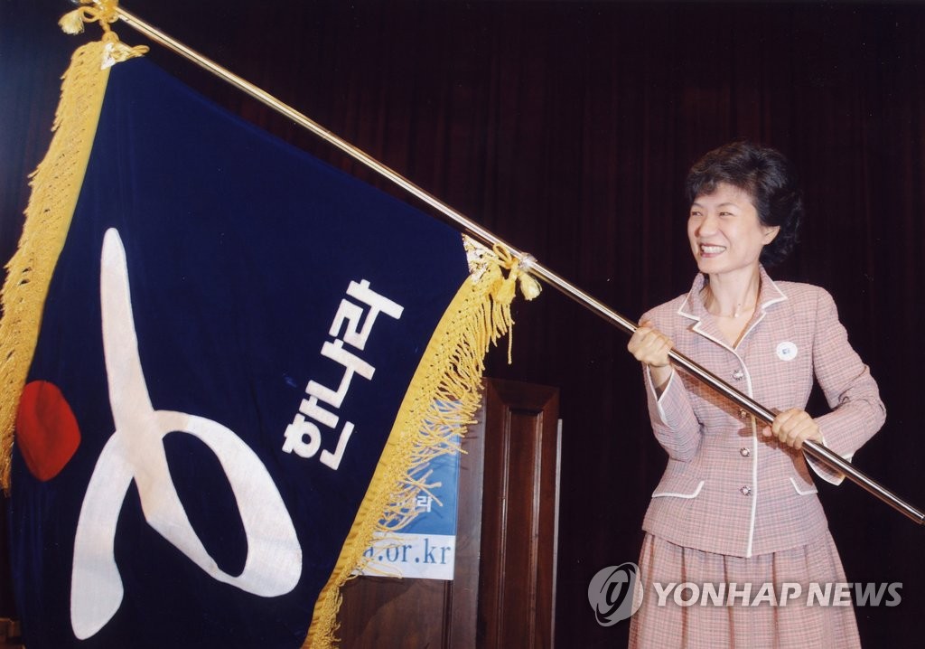 资料图片：2004年，朴槿惠在第17届国会议员当选人大会上挥舞大国家党的党旗。（韩联社）