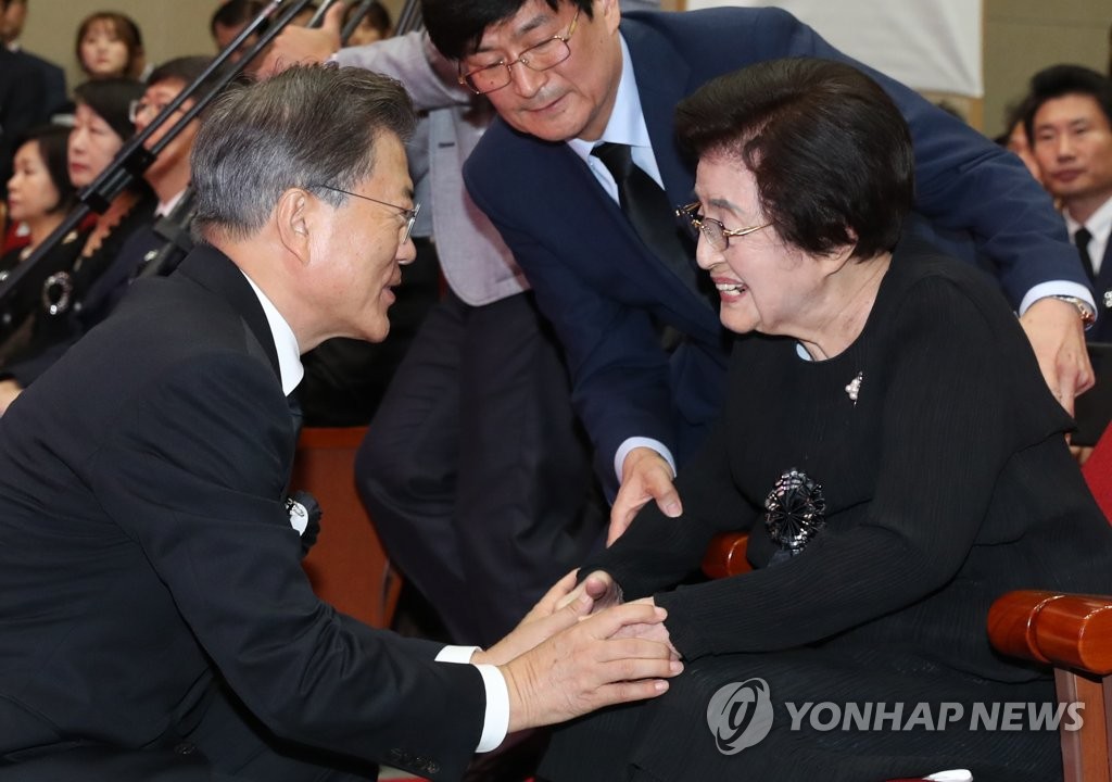 资料图片：2017年8月18日，在前总统金大中逝世8周年追悼仪式上，文在寅（左）与李姬镐握手致意。 韩联社