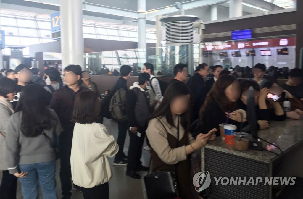 12月23日，在韩国仁川国际机场，浓雾导致航班延误，大量乘客在登机口处等待航空公司通知。（韩联社/读者提供）