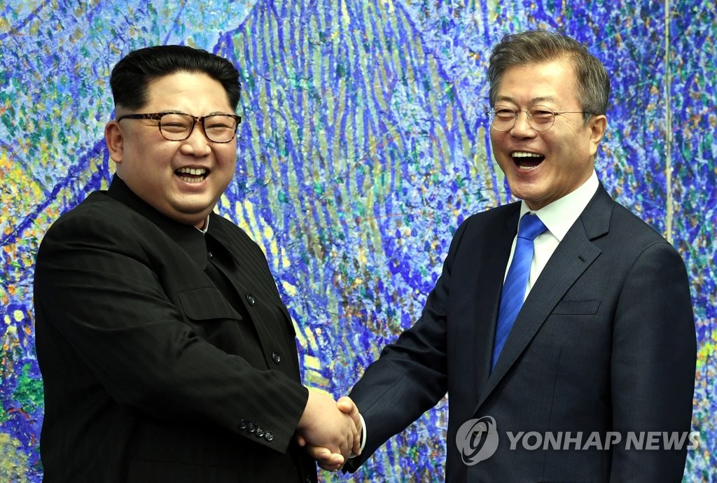资料图片：4月27日，在韩朝边境板门店，韩国总统文在寅（右）同朝鲜国务委员会委员长金正恩在举行会谈前欢笑握手。（韩联社）
