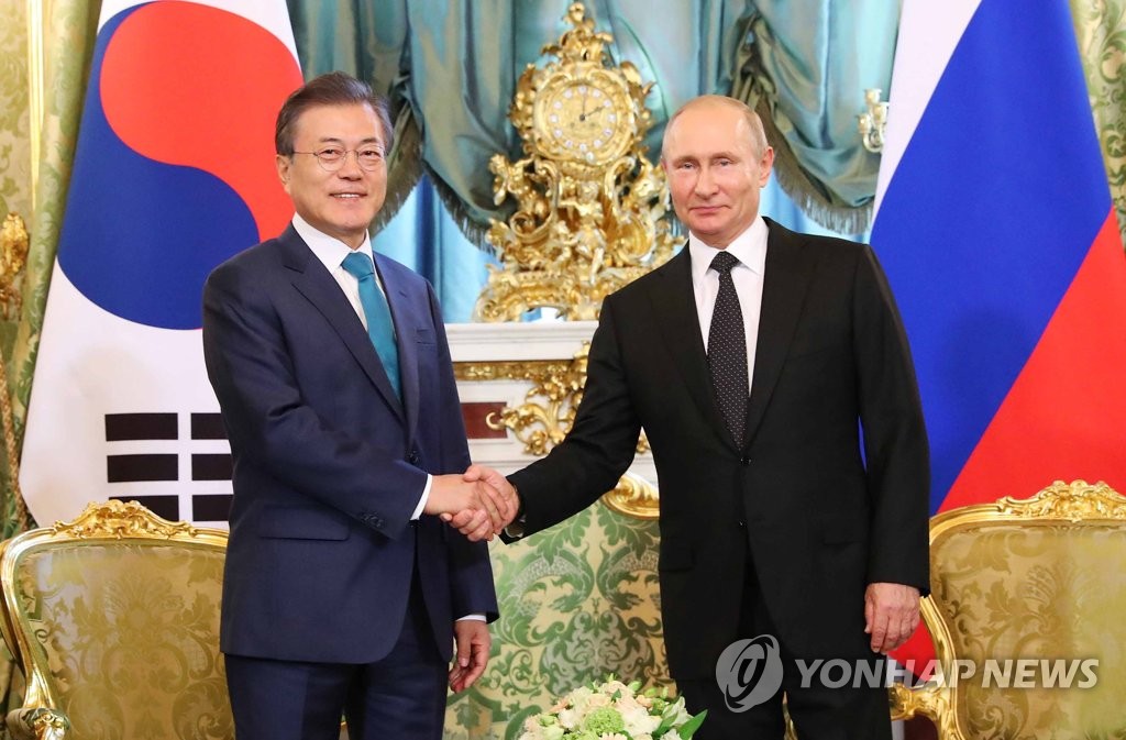 资料图片：当地时间6月22日，在莫斯科克里姆林宫，韩国总统文在寅（左）同俄罗斯总统普京握手合影。（韩联社）