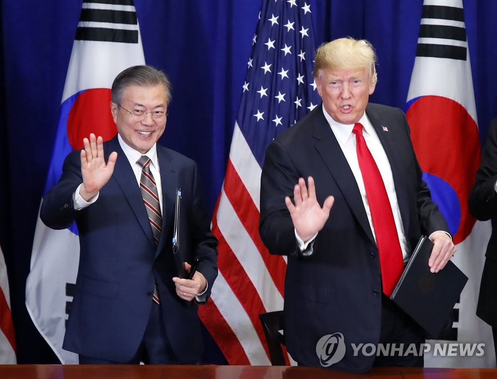 文在寅（左）和特朗普在签署韩美自贸协定修订案后在媒体记者挥手致意。（韩联社）