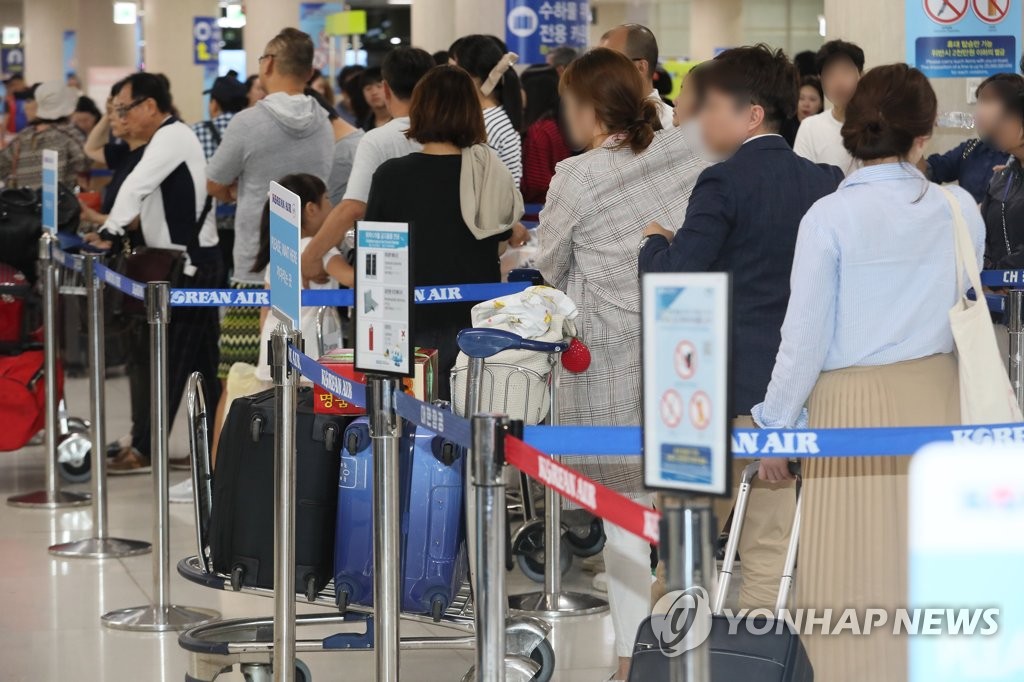 资料图片：2018年9月26日，在济州国际机场，游客排队办理登机手续。（韩联社）