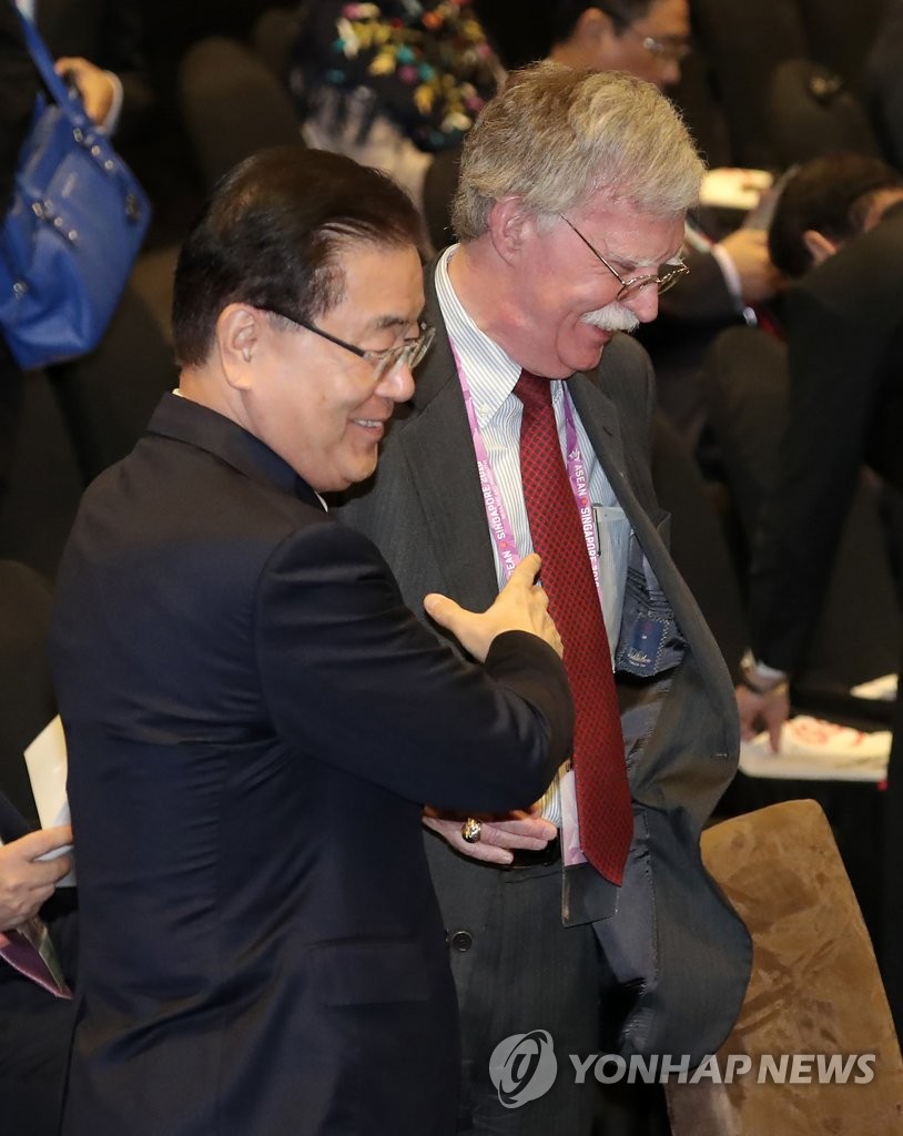 资料图片：2018年11月15日，在新加坡新达会展中心举行的东亚峰会上，郑义溶（左）与博尔顿亲密交谈。（韩联社)