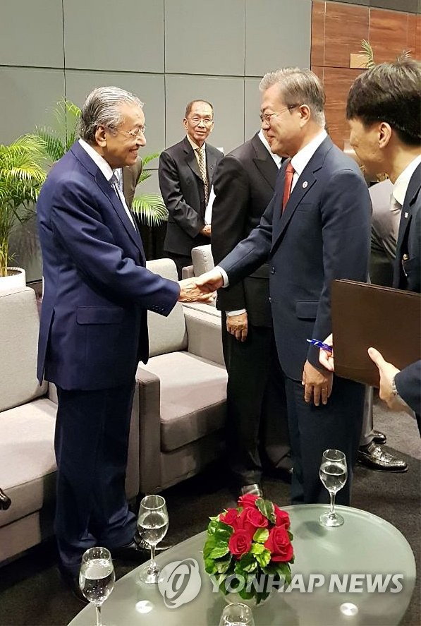 资料图片：2018年11月20日，正在新加坡和巴布亚新几内亚访问的韩国总统文在寅（右）和马来西亚总理马哈蒂尔握手。（韩联社/青瓦台供图）