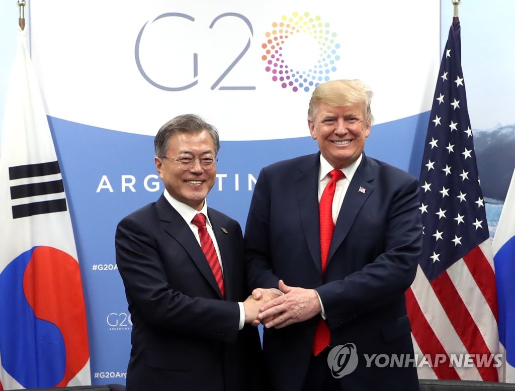 资料图片：当地时间2018年11月30日，在阿根廷布宜诺斯艾利斯，韩国总统文在寅（左）和美国总统特朗普举行会谈，双方亲切握手合影。（韩联社）