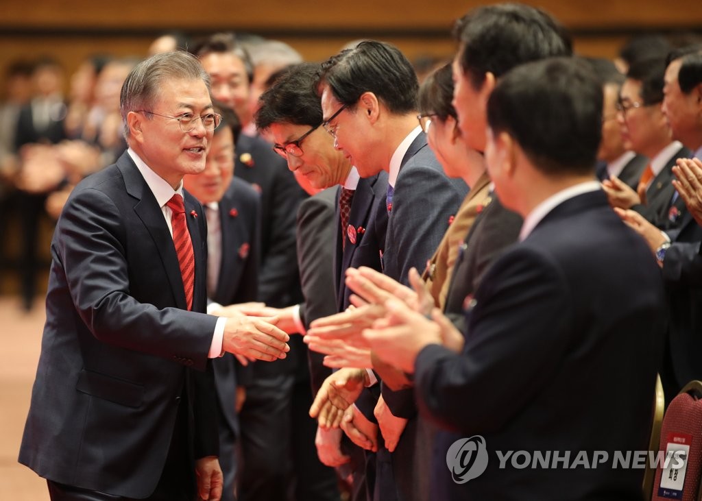 12月7日，在首尔市江南区国际会展中心（COEX），文在寅出席第55个贸易日纪念活动并同出席活动的人士握手。（韩联社）