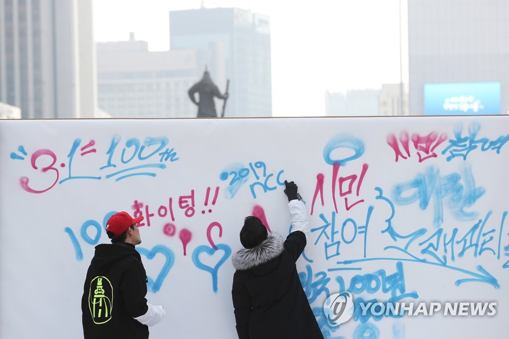 资料图片：2018年12月31日，预告三一运动和大韩国民国临时政府成立将迎百周年的大型留言板设置于首尔光化门广场，两名市民在留言。（韩联社）