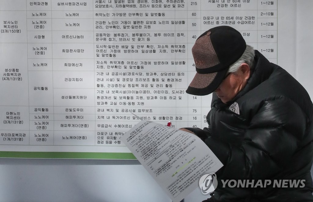 资料图片：一名老年求职者在招聘会上填写求职申请。 韩联社 