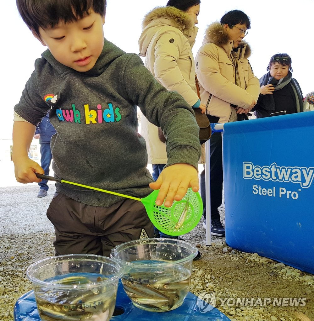 1月28日，在江原道麟蹄郡举行的第19届麟蹄钓冰鱼节上，一名小朋友喜钓冰鱼。（韩联社）