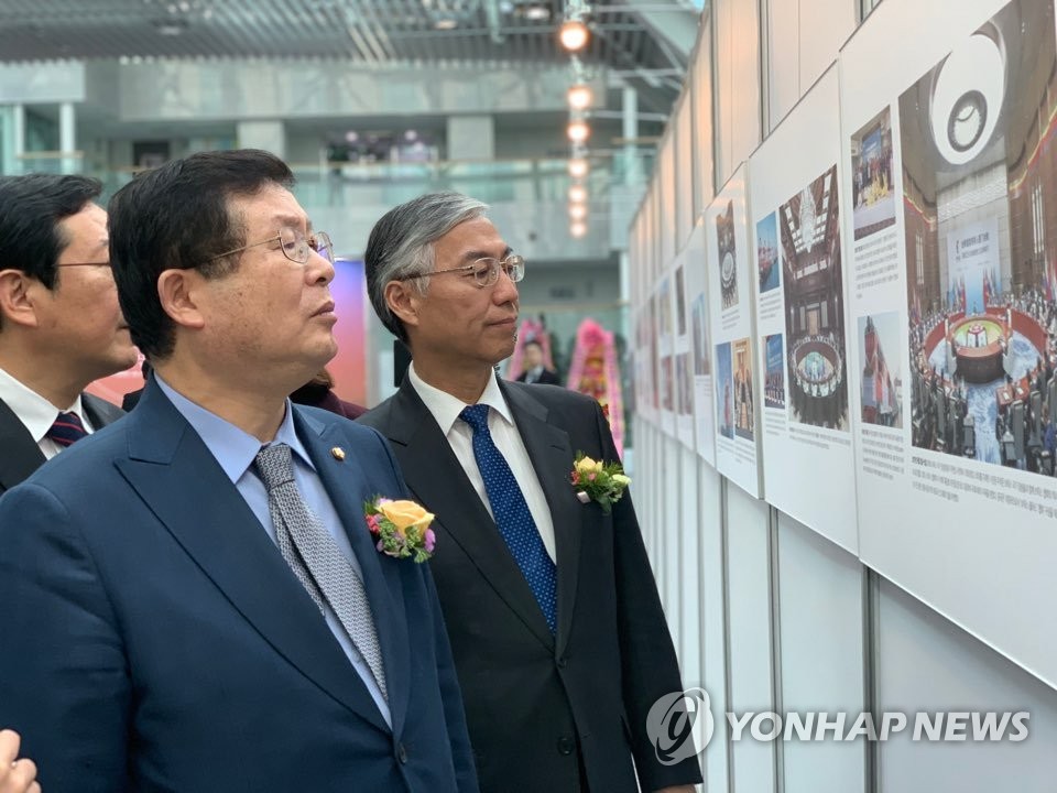 1月31日下午，中国改革开放40年主题国际巡展在韩国国会议员会馆拉开帷幕。图为中国驻韩国大使邱国洪（右）和韩国执政党共同民主党最高委员会委员、国会议员薛勋观展。（韩联社）