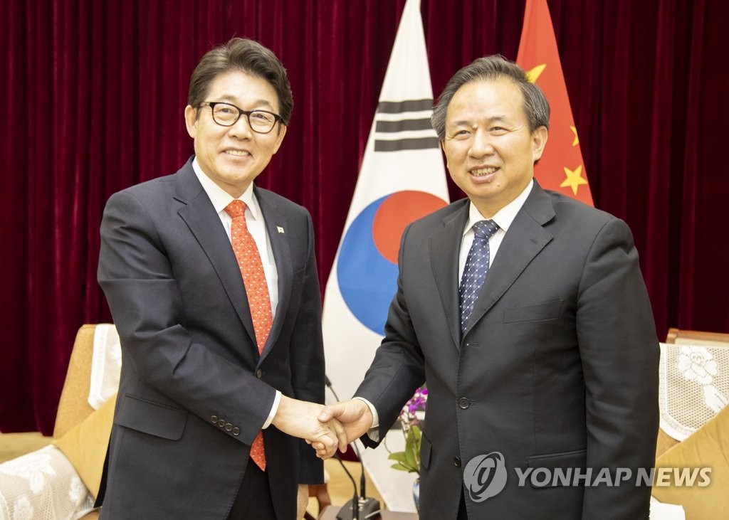 资料图片：2月26日，在北京，韩国环境部长官赵明来（左）同中国生态环境部部长李干杰举行会谈后握手合影。 韩联社/韩国环境部供图