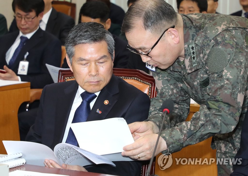 3月18日上午，在国会国防委员会全体会议上，郑景斗（左）与国防部官员翻阅材料。（韩联社）