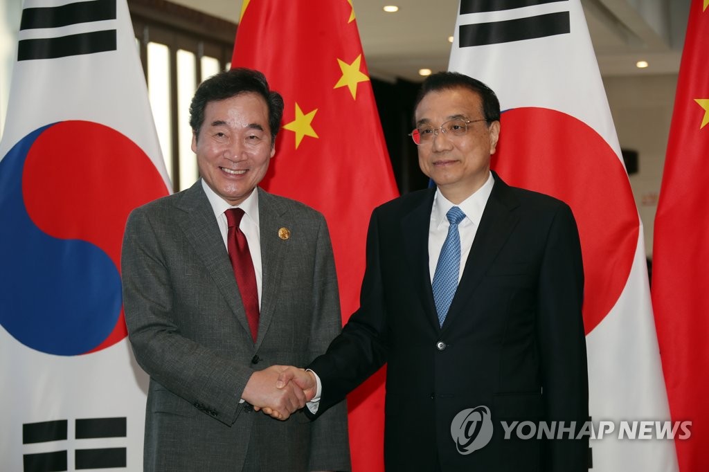 3月27日，在海南，李洛渊（左）与李克强握手。（韩联社）