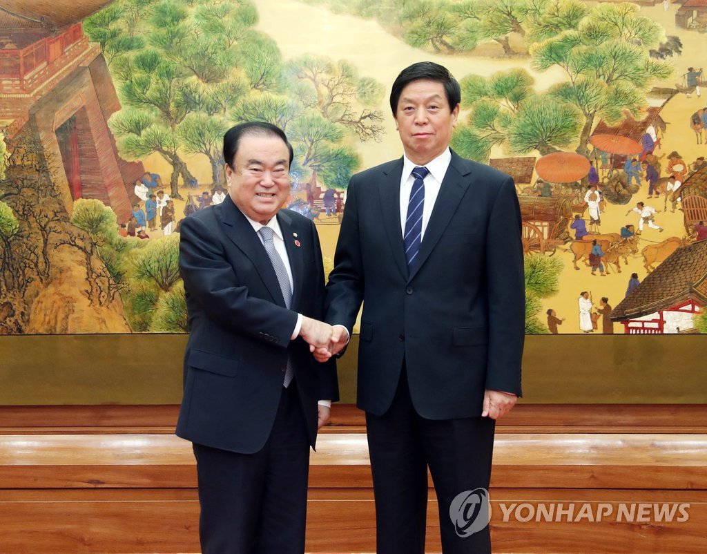 资料图片：文喜相（左）和栗战书亲切握手。（韩联社）