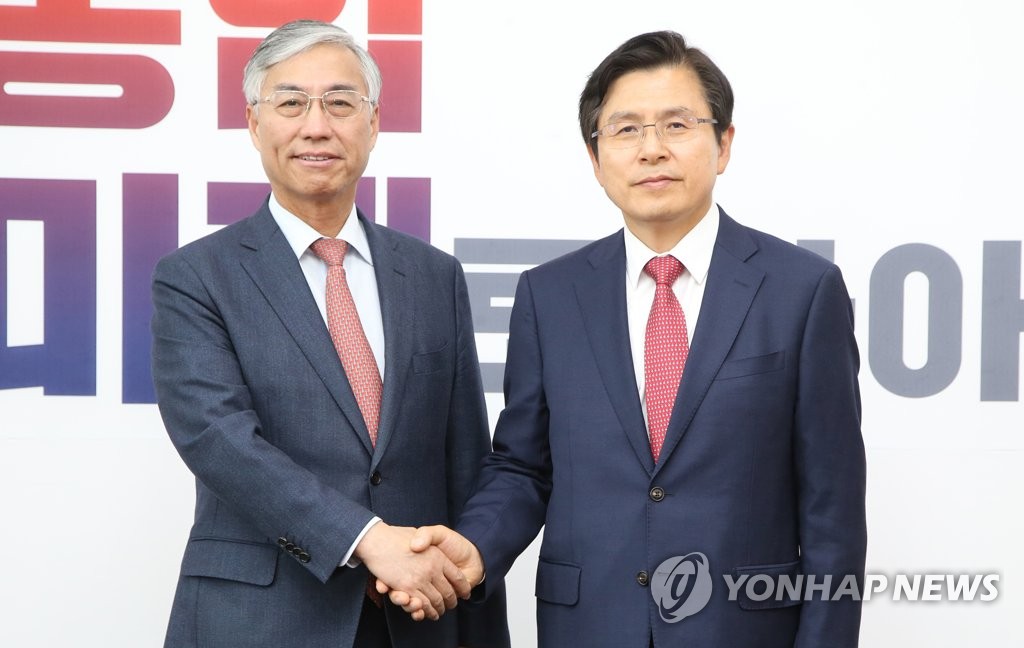 5月16日，在韩国国会，自由韩国党党首黄教安（右）与中国驻韩大使邱国洪握手合影。（韩联社）