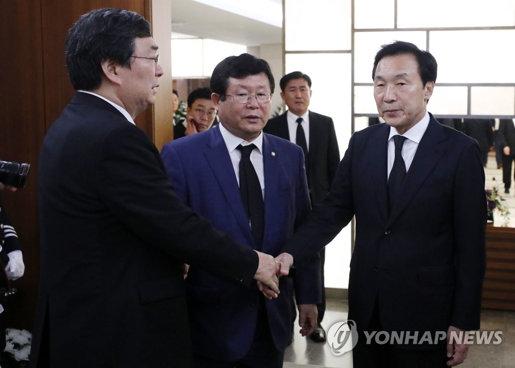 孙鹤圭（右）同李姬镐遗属握手致哀。 韩联社
