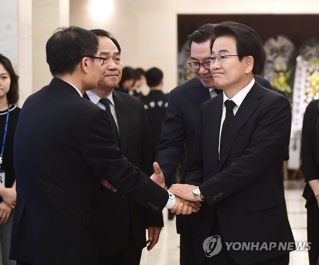 郑东泳（右）同李姬镐遗属握手致哀。 韩联社