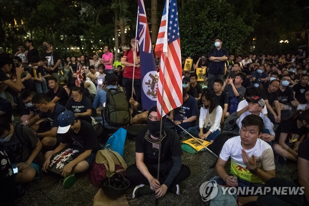 资料图片：香港集会参与者手持美国和英国国旗。 韩联社/欧新社（图片严禁转载复制）