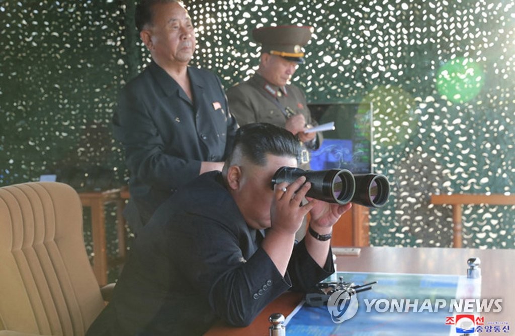 8月24日，金正恩通过望远镜观看超大型火箭炮的试射结果。 韩联社/朝中社（图片仅限韩国国内使用，严禁转载复制）