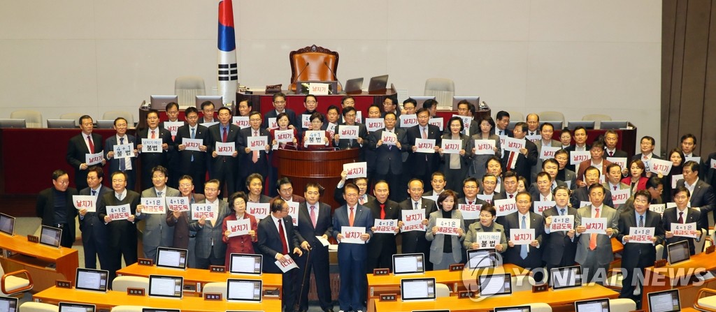 资料图片：12月10日，自由韩国党议员手举牌子，对明年度预算案获得通过表示抗议。 韩联社